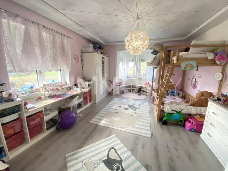 Helles Kinderzimmer mit Etagenbett, Spielzeug und einem gemütlichen Erkerbereich.