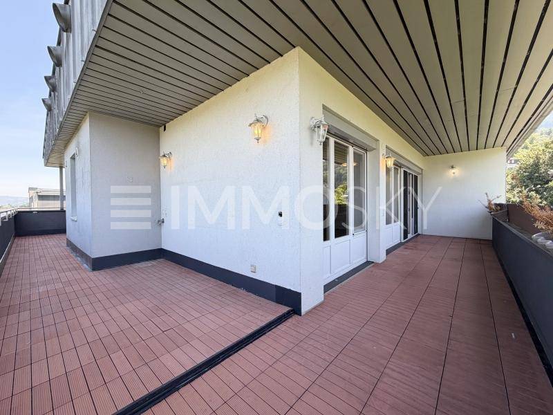 Breite Terrasse mit Fliesenboden, Außenbeleuchtung und Zugang zu den Innenräumen.