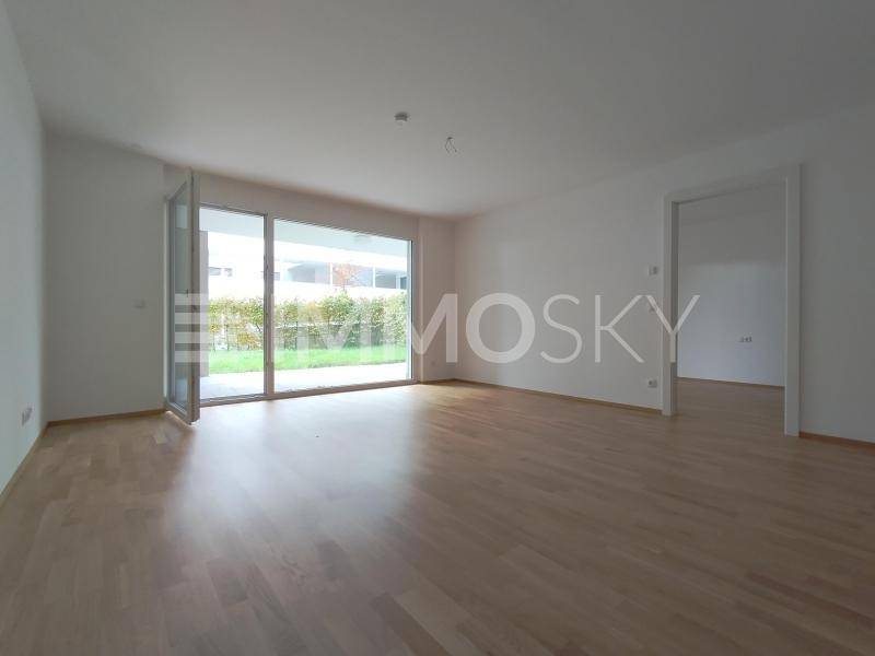 Geräumiger Wohnbereich mit Eichenparkett und großen Fensterfronten mit Blick ins Grüne.