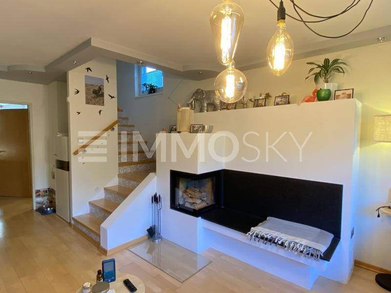 Heller Wohnbereich mit modernem Kamin, integrierter Sitzbank und offener Treppe.