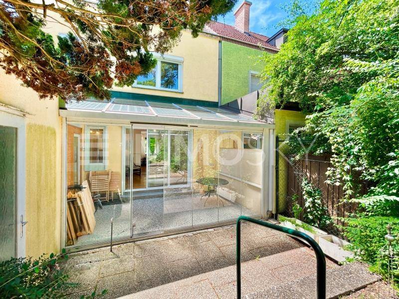 Rückansicht des Hauses mit Wintergarten und gepflegtem Gartenbereich.