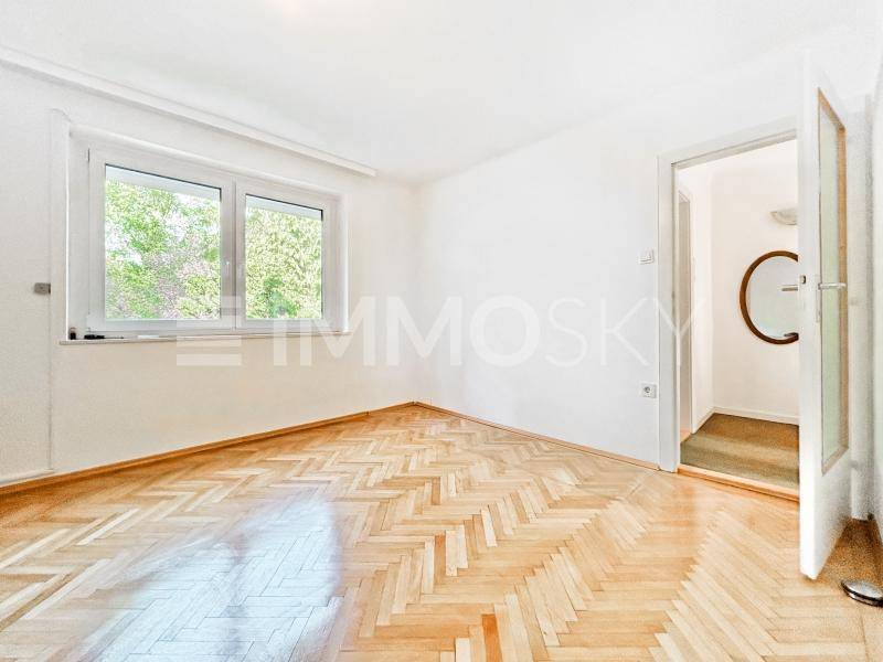 Helles Schlafzimmer mit Fischgrätparkett und Fensterblick ins Grüne.