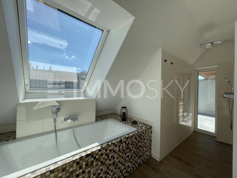 Helles Badezimmer mit Badewanne, Dusche und großem Dachfenster für viel Tageslicht.