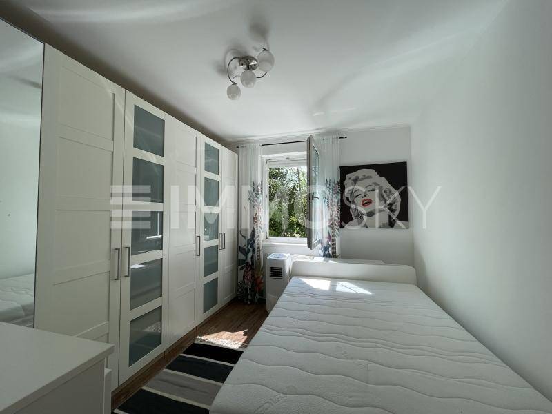 Helles Schlafzimmer mit großem Kleiderschrank, Einzelbett und Fenster mit Blick ins Grüne.