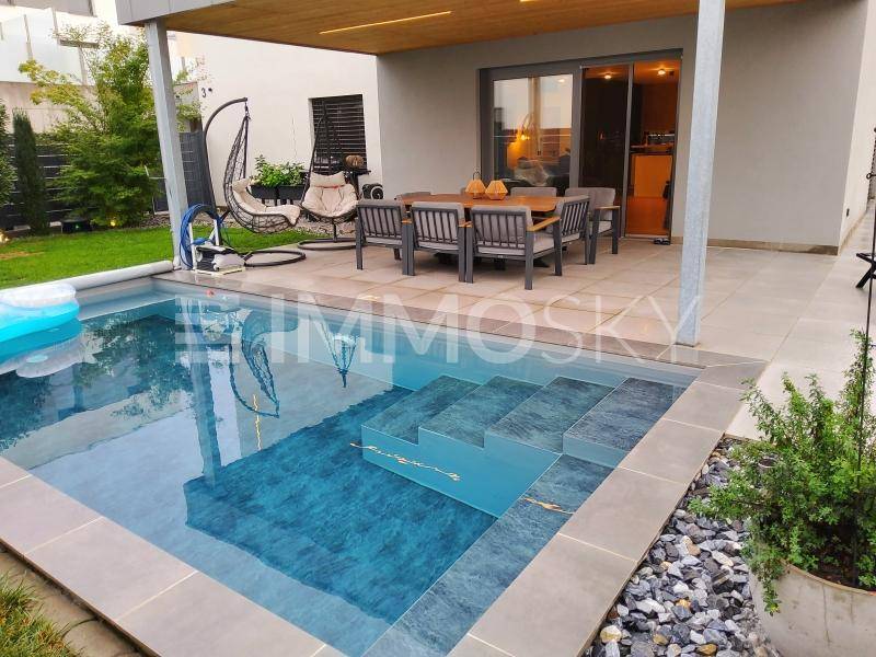 Außenbereich mit modernem Pool, gefliester Terrasse und Essbereich im Freien.