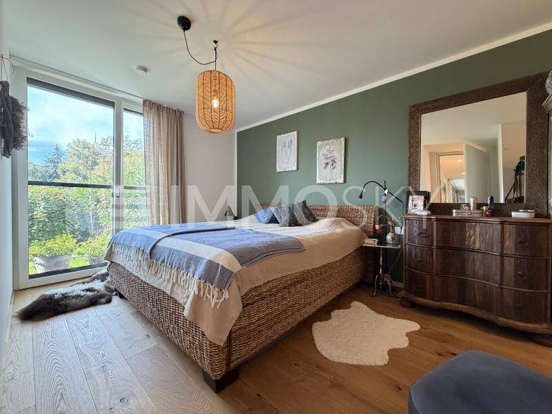 Gemütliches Schlafzimmer mit Holzboden, grüner Akzentwand und Blick ins Grüne.