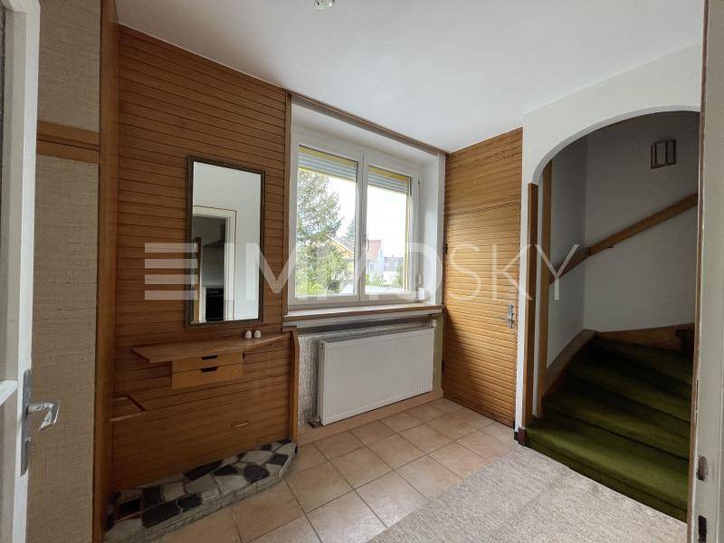 Gemütlicher Eingangsbereich mit Holzvertäfelung, Fliesenboden und Treppenaufgang.