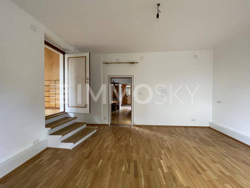 Helles und geräumiges Wohnzimmer mit Parkettboden und Zugang zu weiteren Räumen.