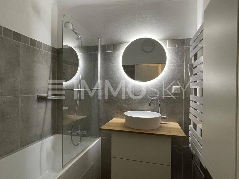 Modernes Badezimmer mit Badewanne, beleuchtetem Spiegel und stilvollem Waschbecken auf Holzplatte.