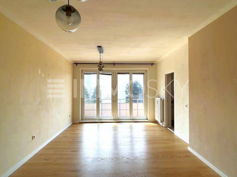 Geräumiges, leeres Wohnzimmer mit hellem Holzboden und großen Fenstertüren zum Außenbereich.
