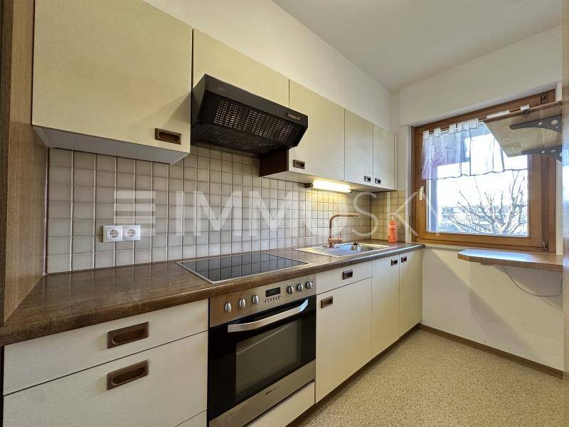 Funktionale Küche mit hellen Schränken, integrierten Geräten und einem Fenster für Tageslicht.