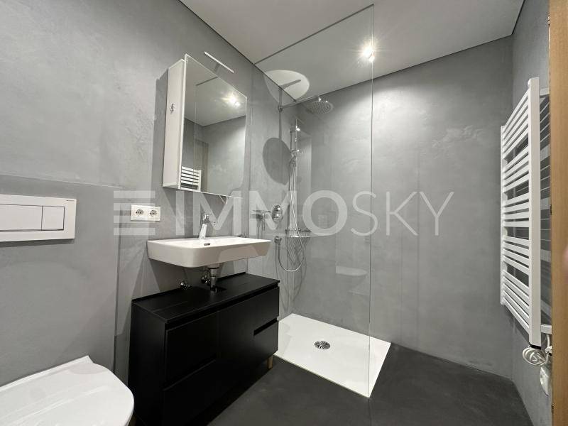 Modernes Badezimmer mit begehbarer Dusche, Waschbecken und beheiztem Handtuchhalter.