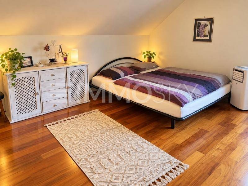 Schlafzimmer im Dachgeschoss mit Holzboden, einem Doppelbett und einer weißen Kommode unter der Dachschräge.