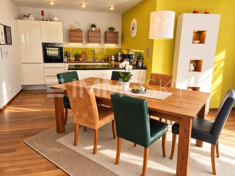 Heller Essbereich mit Holztisch und bunten Stühlen, direkt an die moderne Küche angrenzend und offen gestaltet.