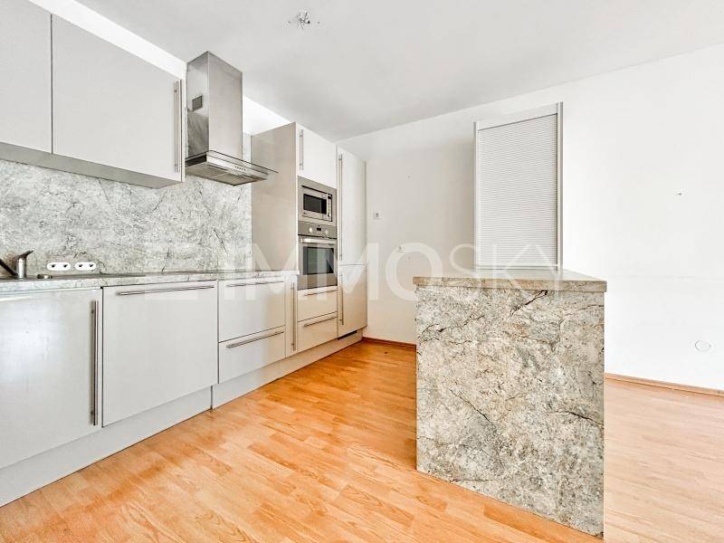 Moderne Einbauküche mit weißen Schränken, Dunstabzugshaube und einer Kücheninsel mit Steinoptik.