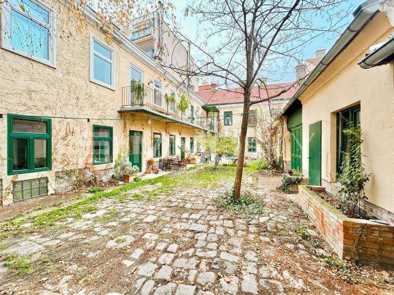 Gepflasterter Innenhof mit Bäumen und der Rückseite eines historischen Gebäudes.