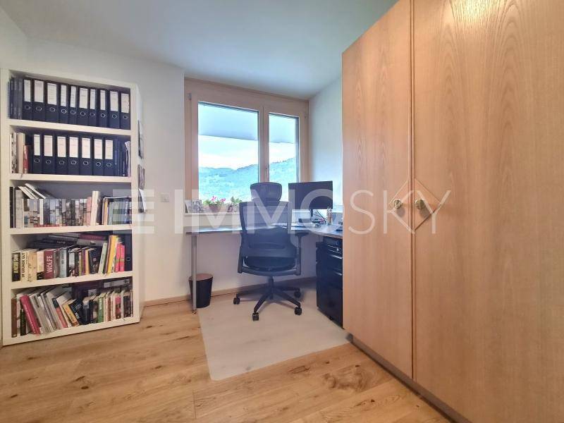 Funktionales Arbeitszimmer mit Holzboden, großem Schrank und einem Fenster mit Blick ins Grüne.