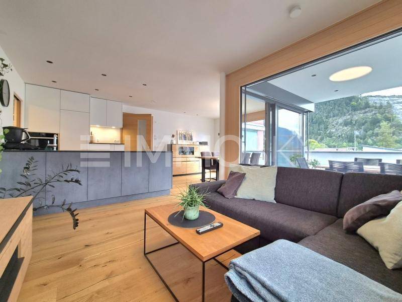 Heller Wohnbereich mit gemütlichem Sofa, Holzboden und direktem Zugang zu einem Balkon mit Bergblick.