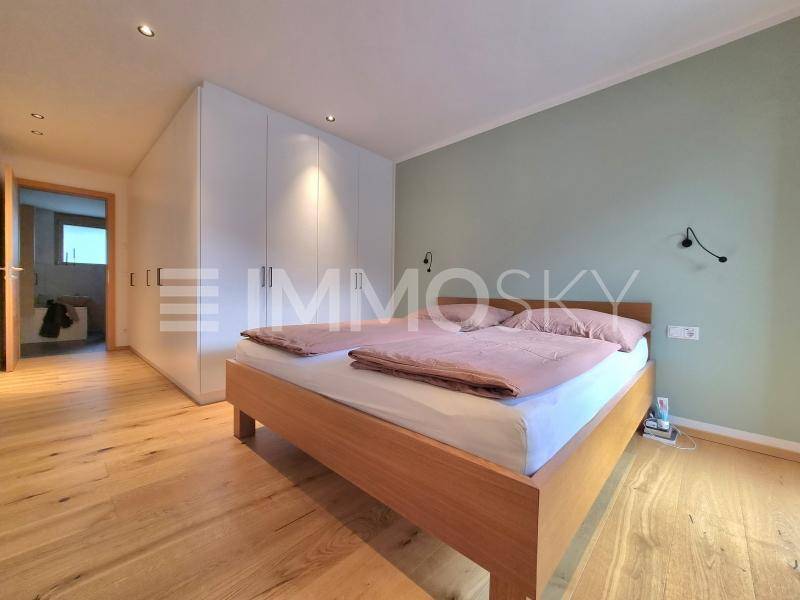 Schlafzimmer mit Holzboden, integrierten weißen Kleiderschränken und direktem Zugang zum Badezimmer.
