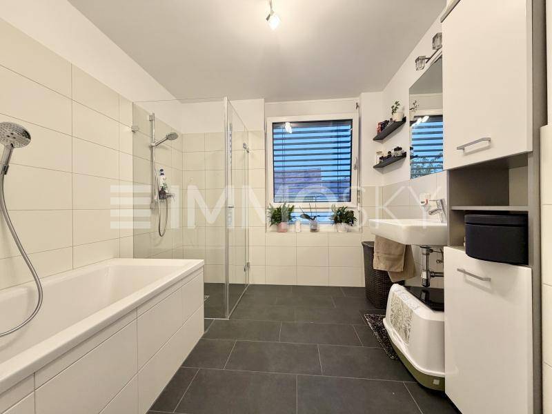 Modernes Badezimmer mit Badewanne, ebenerdiger Dusche, Einzelwaschbecken und Fenster.