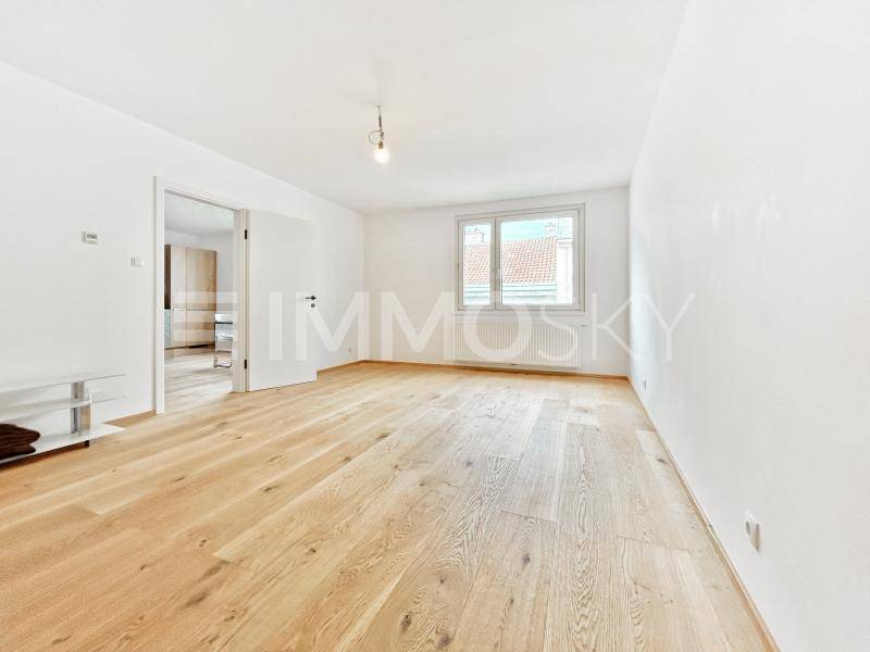 Heller, leerer Raum mit Holzfußboden und großem Fenster, bereit zur individuellen Gestaltung.