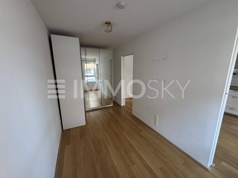 Helles Schlafzimmer mit Parkettboden und einem großen Spiegelschrank.