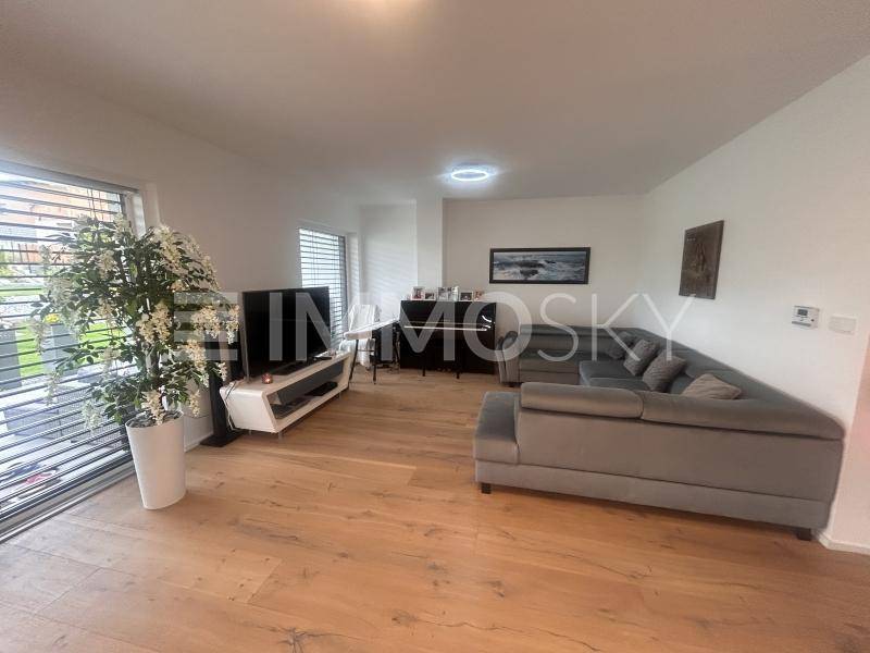 Geräumiges Wohnzimmer mit Holzboden, bequemer Couch und Zugang zur Terrasse.