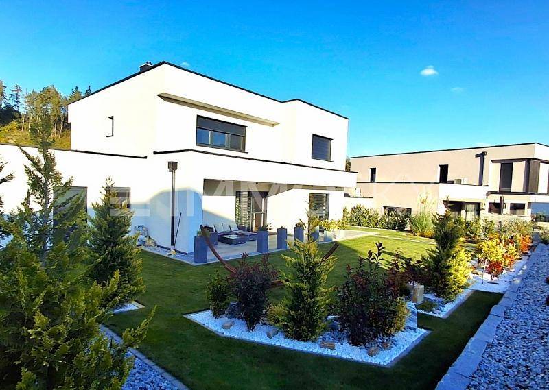 Zeitgenössische Villa mit weißer Fassade, großem Garten und gemütlicher Terrasse mit Blick ins Grüne.