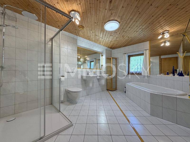 Badezimmer mit Duschkabine, Badewanne, Doppelwaschbecken und Holzdecke.
