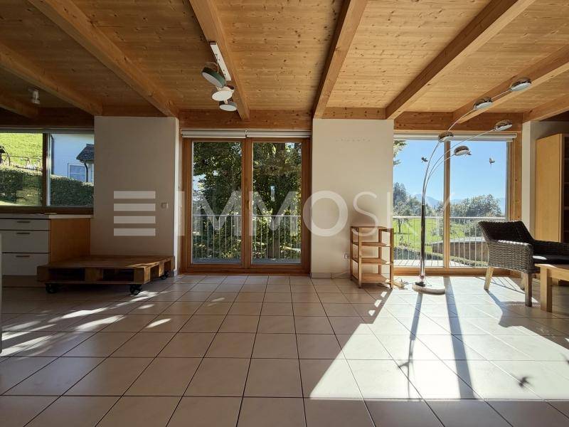 Geräumiges Wohnzimmer mit Fliesenboden, Holzbalkendecke und Zugang zum Balkon.