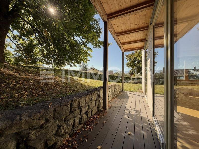 Überdachte Holzterrasse mit Blick ins Grüne und viel Sonnenschein.