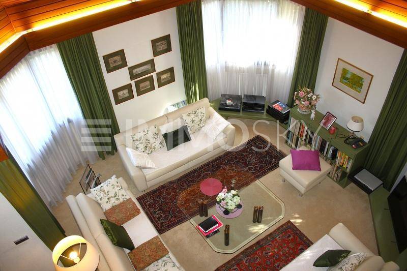 Helles Wohnzimmer mit hohen Holzdecken, großen Fenstern und gemütlichen Sofas.