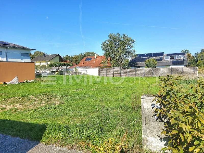 Sonniges Baugrundstück mit angrenzender Bebauung und grüner Landschaft.