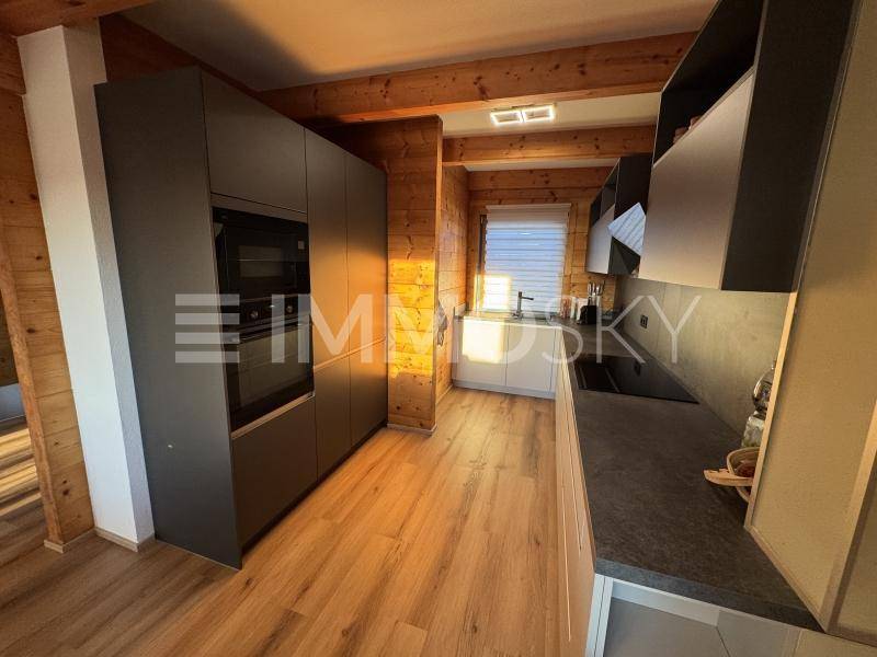 Moderne Küche mit dunklen Einbauschränken, Holzwänden und integrierten Geräten.