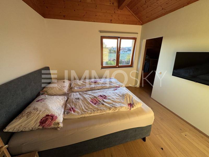 Gemütliches Schlafzimmer mit Holzdachschräge, Holzboden und Blick ins Grüne.