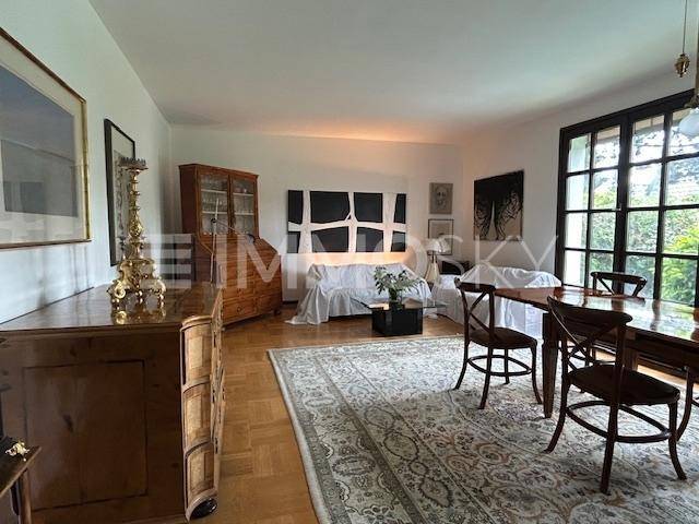 Geräumiger Wohn-Essbereich mit klassischem Parkettboden, eleganten Möbeln und großen Fenstern.