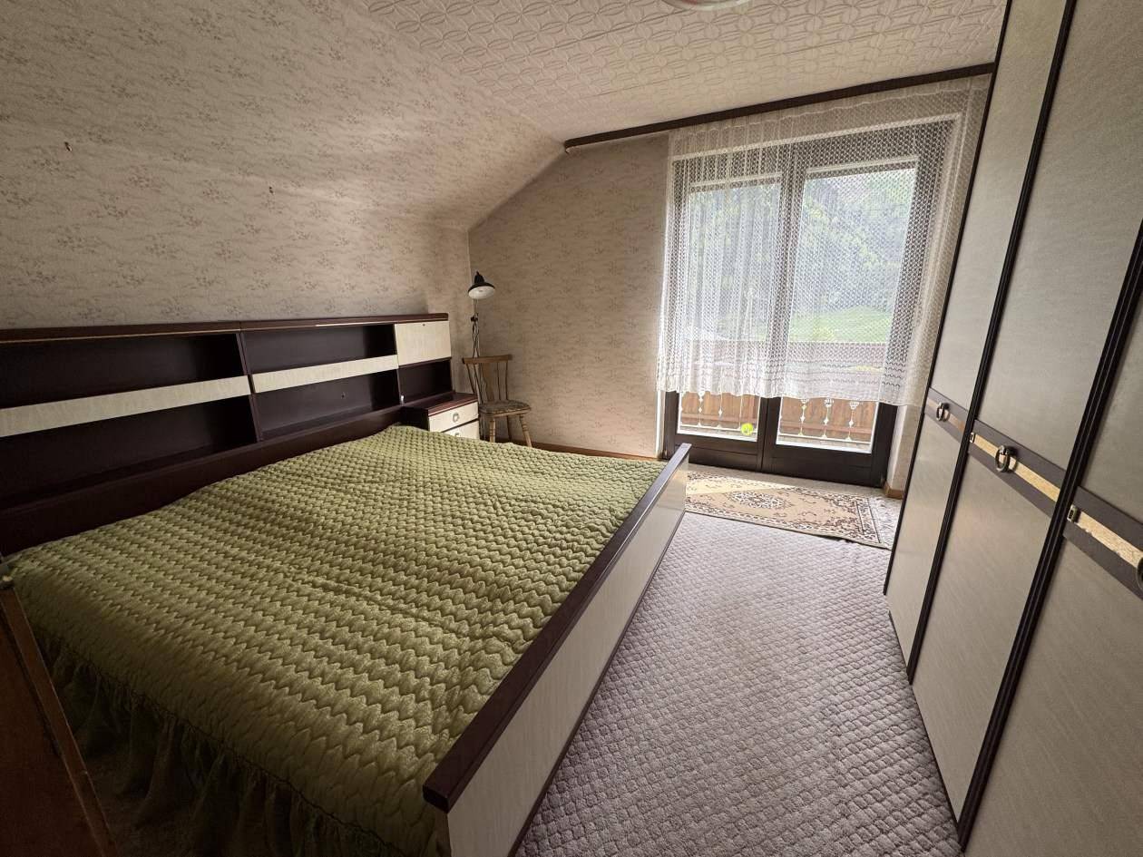 Schlafzimmer mit Teppichboden, Einbauschränken und Balkonzugang mit Blick ins Grüne.