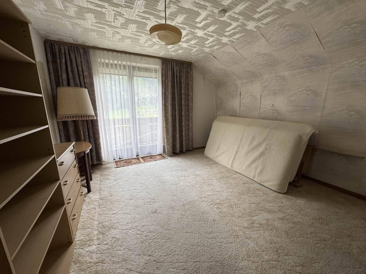 Geräumiges Zimmer mit Teppichboden, Dachschräge und Zugang zu einem Balkon mit Ausblick.