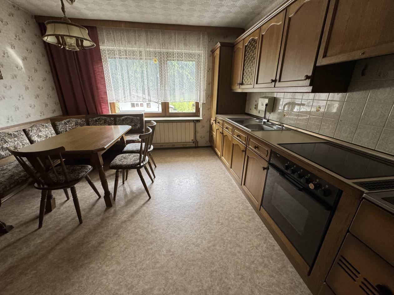 Gemütliche Wohnküche im traditionellen Stil mit Holzeinbauten, Essecke und Blick ins Grüne.
