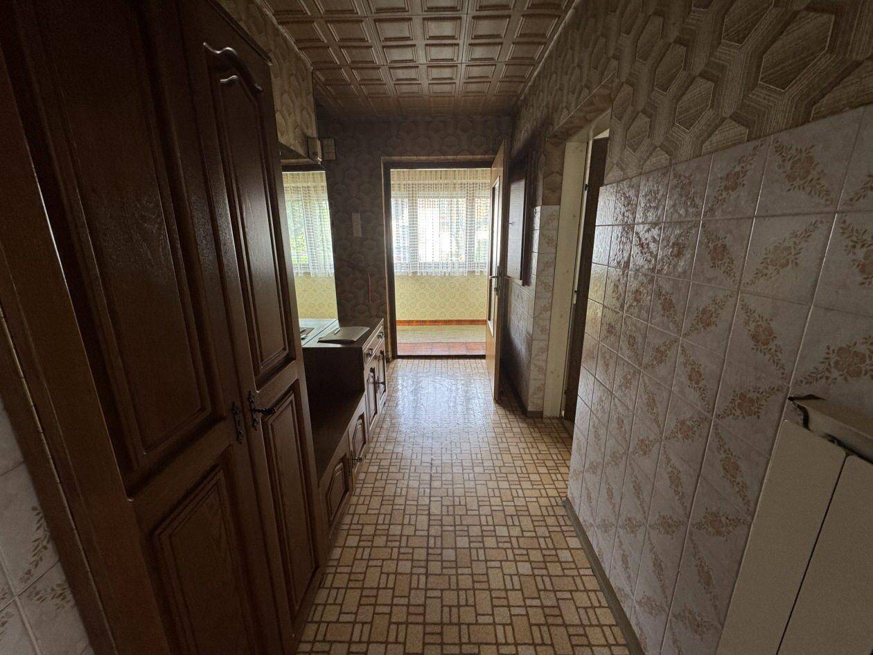 Flur mit Holzschränken, gemusterten Tapeten und Fliesenboden im traditionellen Stil.