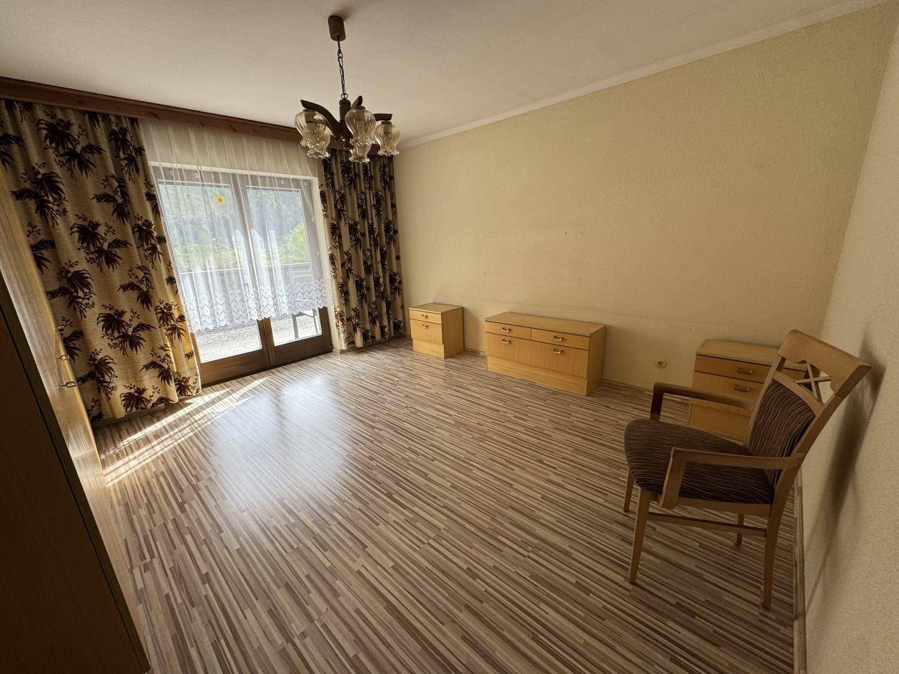 Helles Zimmer mit Laminatboden, großen Fenstern und Zugang zu einem Balkon mit Ausblick.
