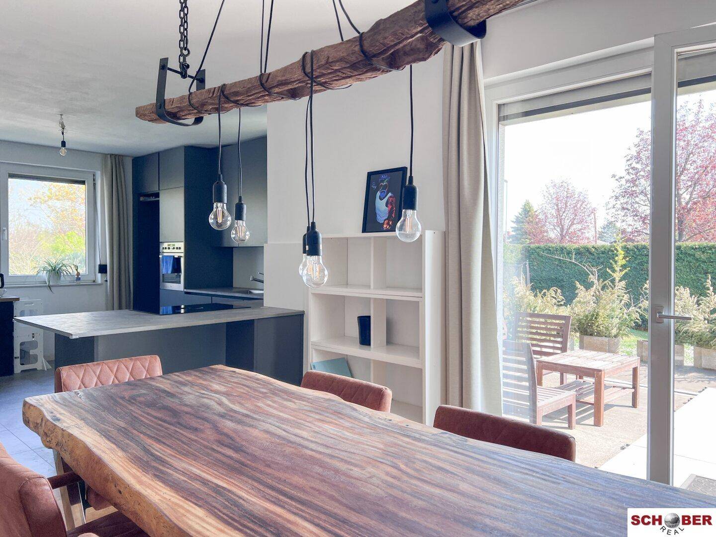 Heller Essbereich mit Holztisch und Zugang zur Terrasse, angrenzend an die moderne Küche.