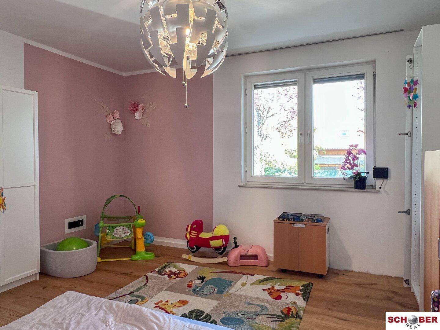 Kinderzimmer mit Holzboden, farbiger Wandgestaltung und Spielzeug.