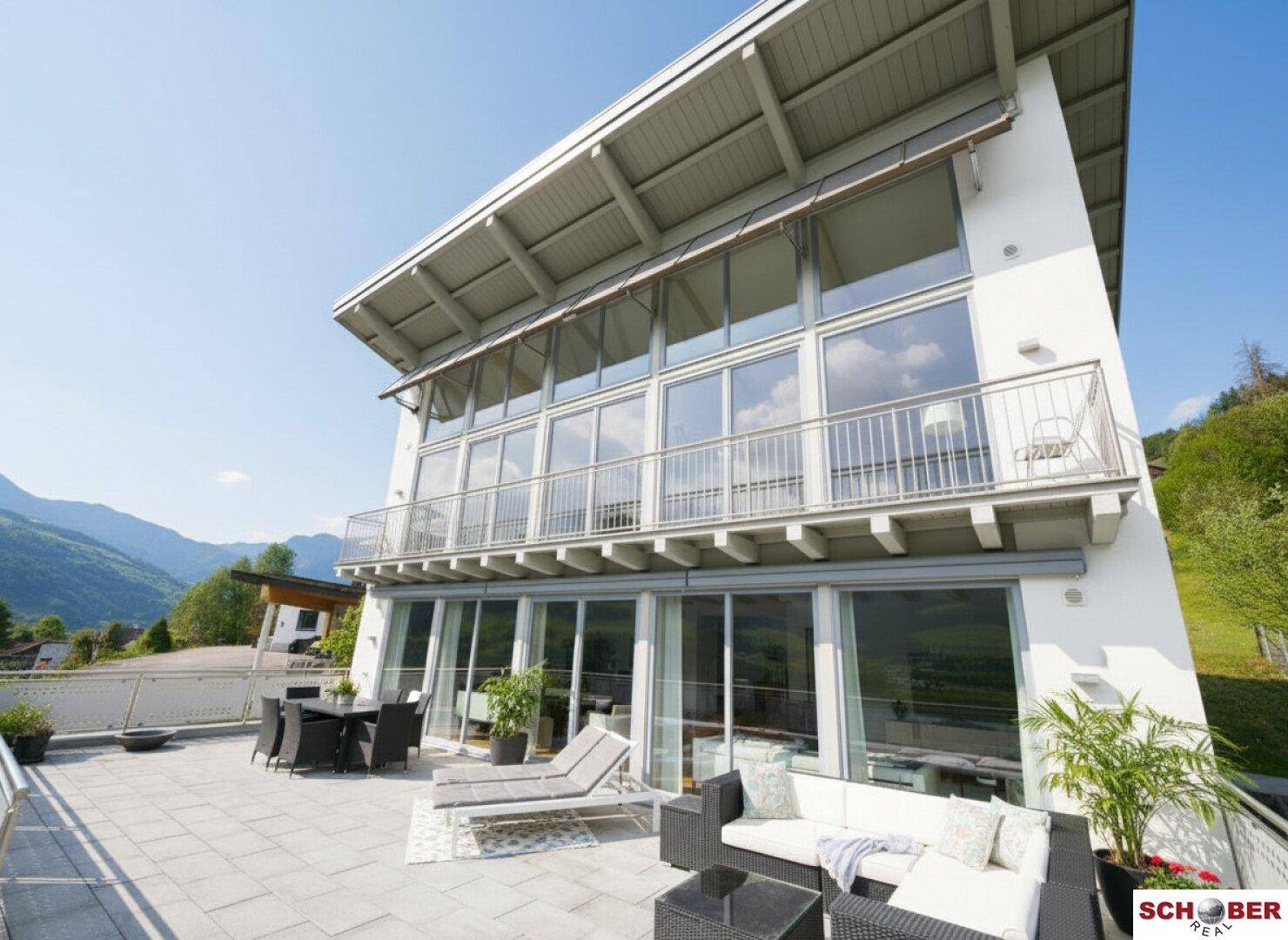 Moderne Architektur mit großer Terrasse und Bergblick unter blauem Himmel.