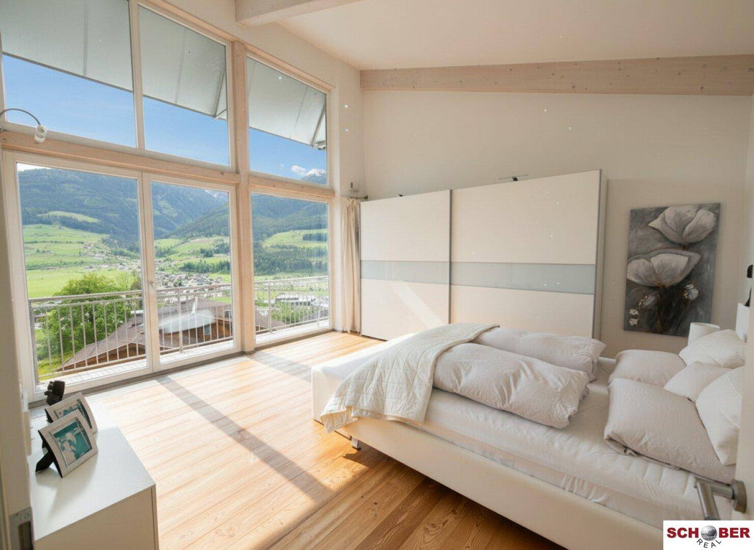 Lichtdurchflutetes Schlafzimmer mit Panoramablick auf die umliegende Bergwelt.