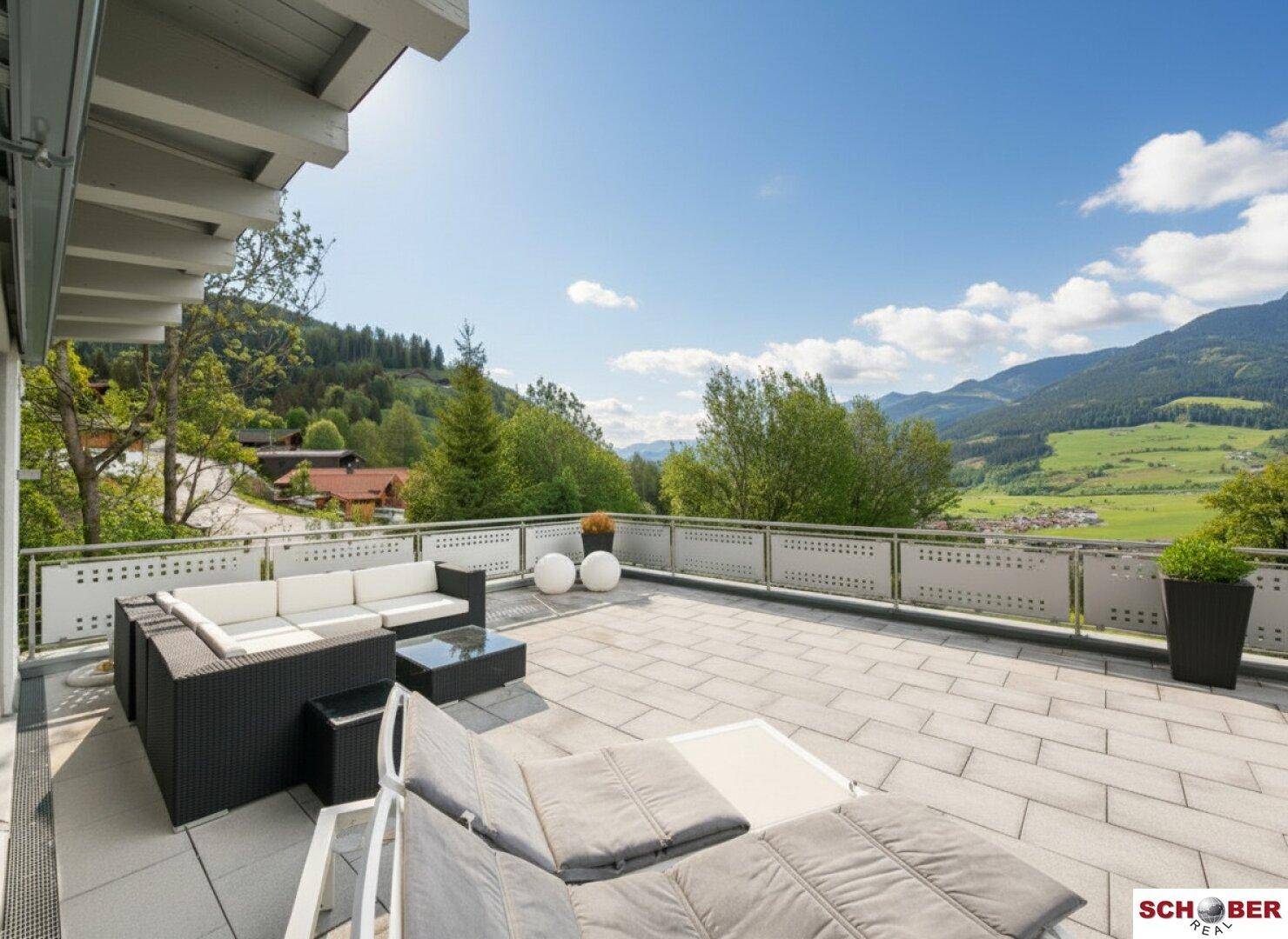 Große Sonnenterrasse mit Lounge-Möbeln und weitem Blick auf die Berge.