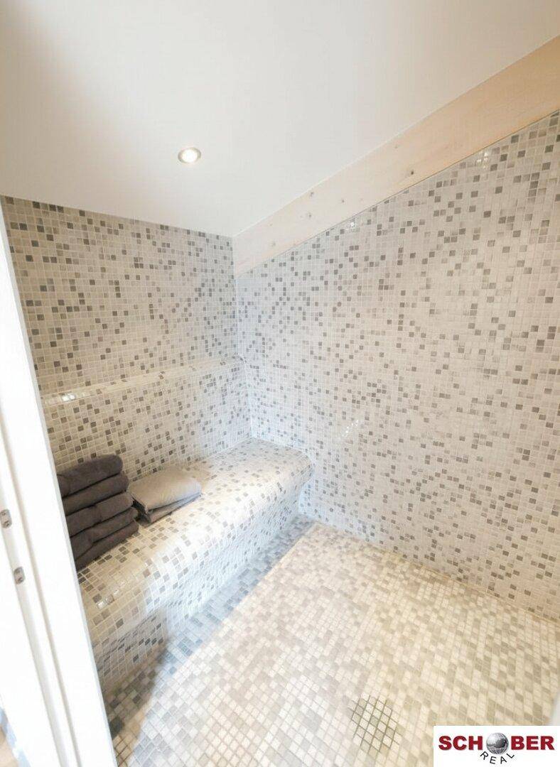 Moderner Dampfbadbereich mit Mosaikfliesen und Sitzgelegenheiten.