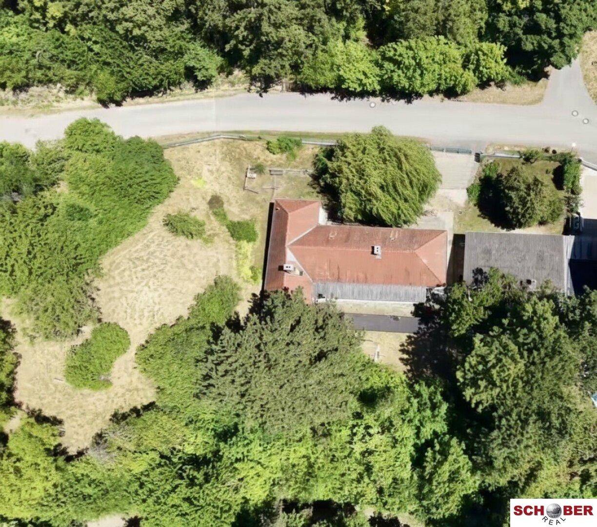 Luftaufnahme des Anwesens mit Haus, Nebengebäuden und umgebender Waldlandschaft.