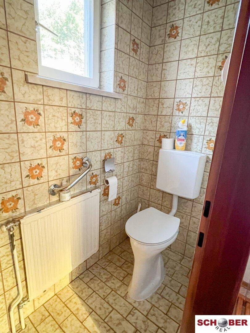 Separate Toilette mit WC, Heizkörper und gemusterten Fliesen im traditionellen Stil.