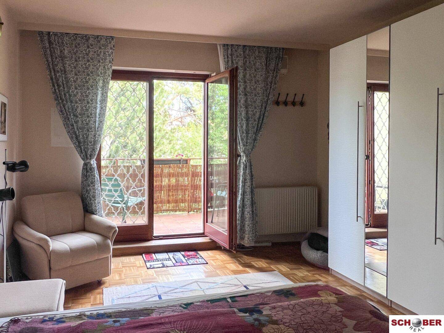 Schlafzimmer mit Parkettboden, großem Kleiderschrank und Zugang zum Balkon.
